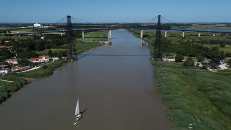 volando lejos del puente de rochefort revelando un velero y aves que pasan, francia