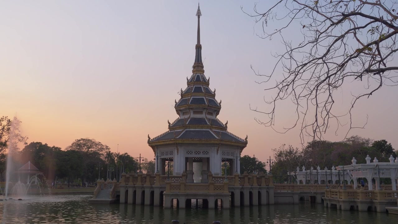 Stabil udsigt over en traditionel thailandsk pavillon omgivet af vand i Chaloem Kanchanaphisek Park ved solnedgang i Nonthaburi, Thailand.
