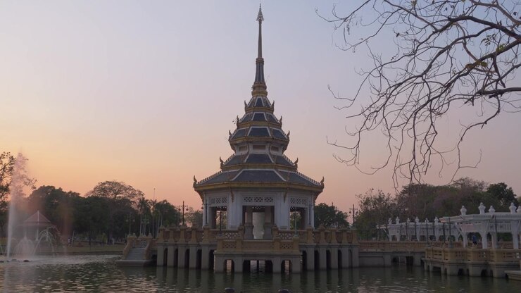 Stabil udsigt over en traditionel thailandsk pavillon omgivet af vand i Chaloem Kanchanaphisek Park ved solnedgang i Nonthaburi, Thailand.