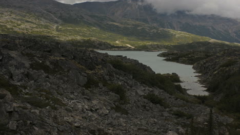 A-calm-rocky-river-with-mountains-encased-in-fog-in-the-distance-in-Skagway,-Alaska