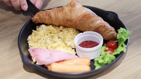 croissant, scrambled eggs, and ham on a plate