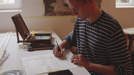 young architecture student drawing sketch with pencil at his desk