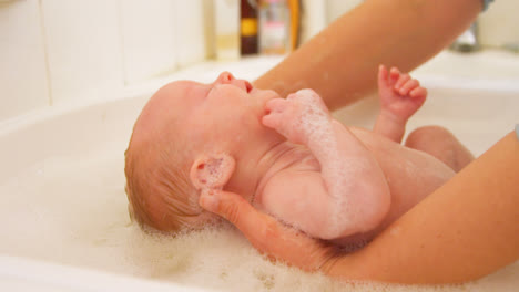 mother giving her baby boy a bath in bathroom 4k