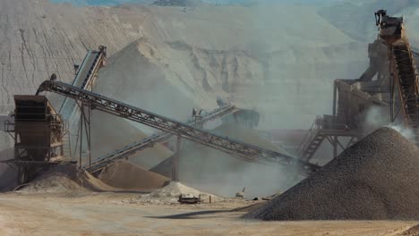 industrial sand mining - 2 clips, long shot stone crusher (rock stone crushing machines) belt is rolling and dropping off gravels on a pile of gravels.