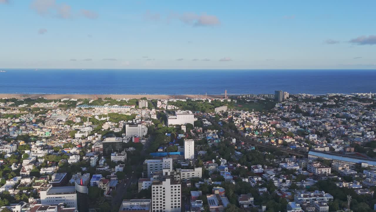 An aerial perspective of Chennai in the morning would showcase the city's tranquil beauty, as the sun casts a golden glow over its sprawling urban landscape. Marina beach with city view.