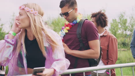 grupo de jóvenes amigos esperando detrás de la barrera en la entrada al sitio del festival de música