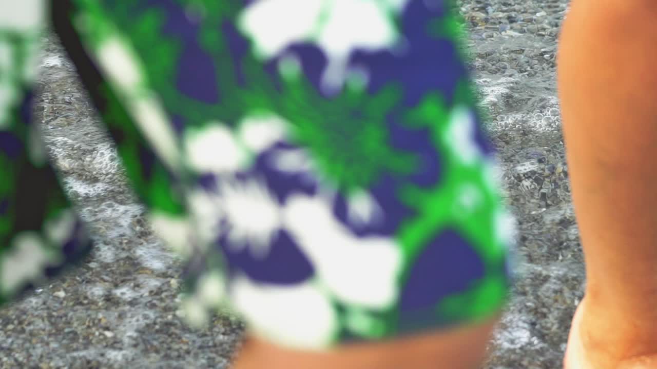 People step barefoot along the shore in the wet sand and waves. Sea walk near water. Close-up.