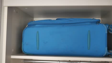 blue suitcase stored in closet