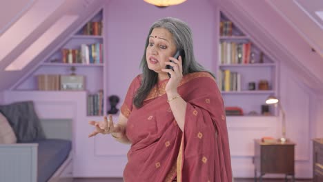 una anciana india enojada gritando en el teléfono.