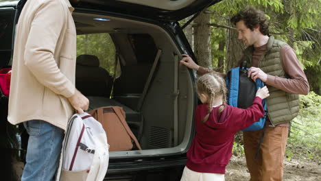 blonde girl giving backpacks to her parents