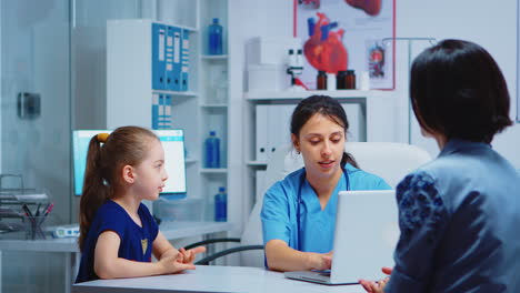 nurse talking with child and writing on laptop
