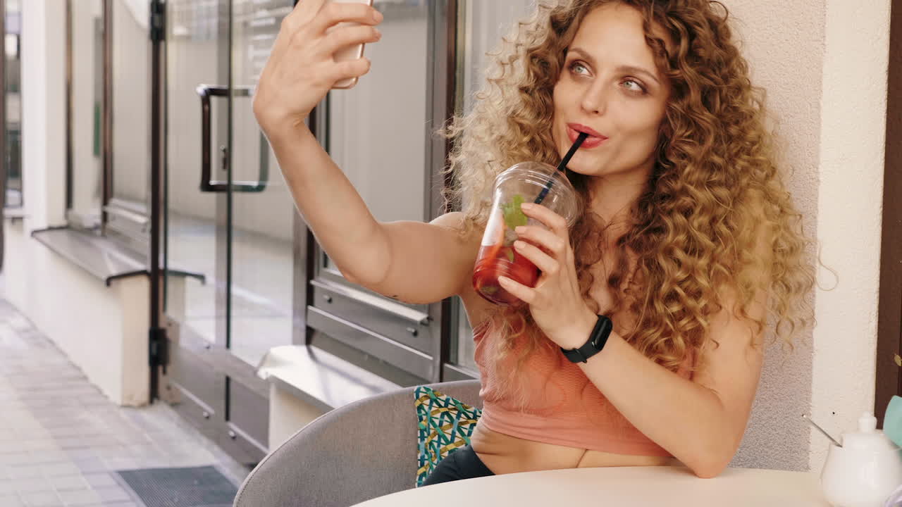 Donna che si fa un selfie mentre si gode un drink all'aperto.