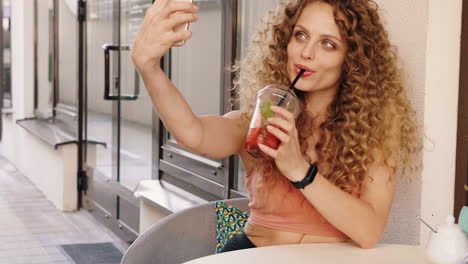 mujer tomando una selfie mientras disfruta de una bebida al aire libre