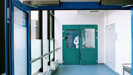 médico de sexo masculino sosteniendo un clipboard y caminando en el pasillo del hospital