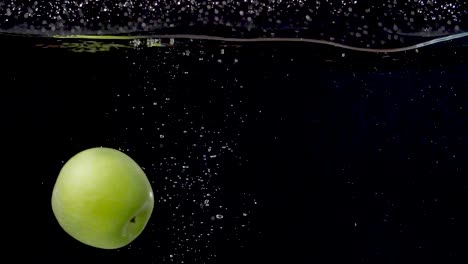 vibrant green apple being dropped into water in slow motion