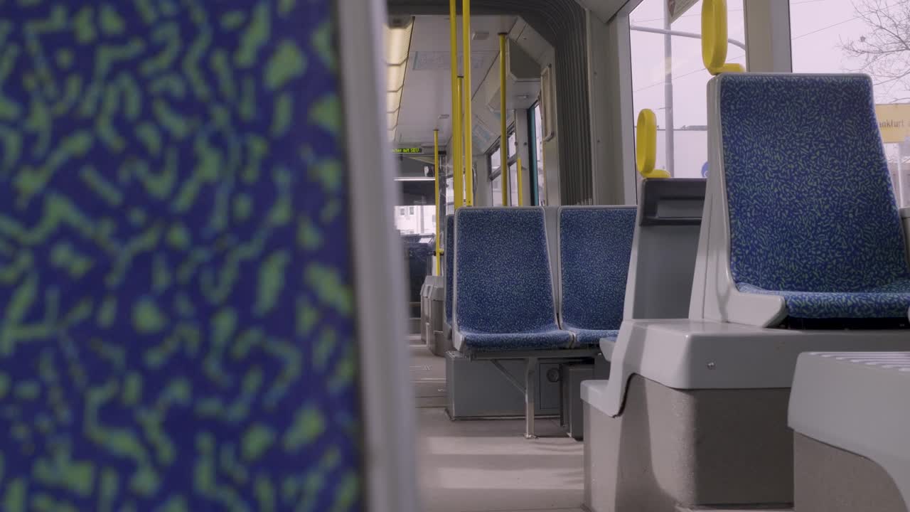 Empty tram interior with colorful seating and yellow poles, shot in Frankfurt, Germany