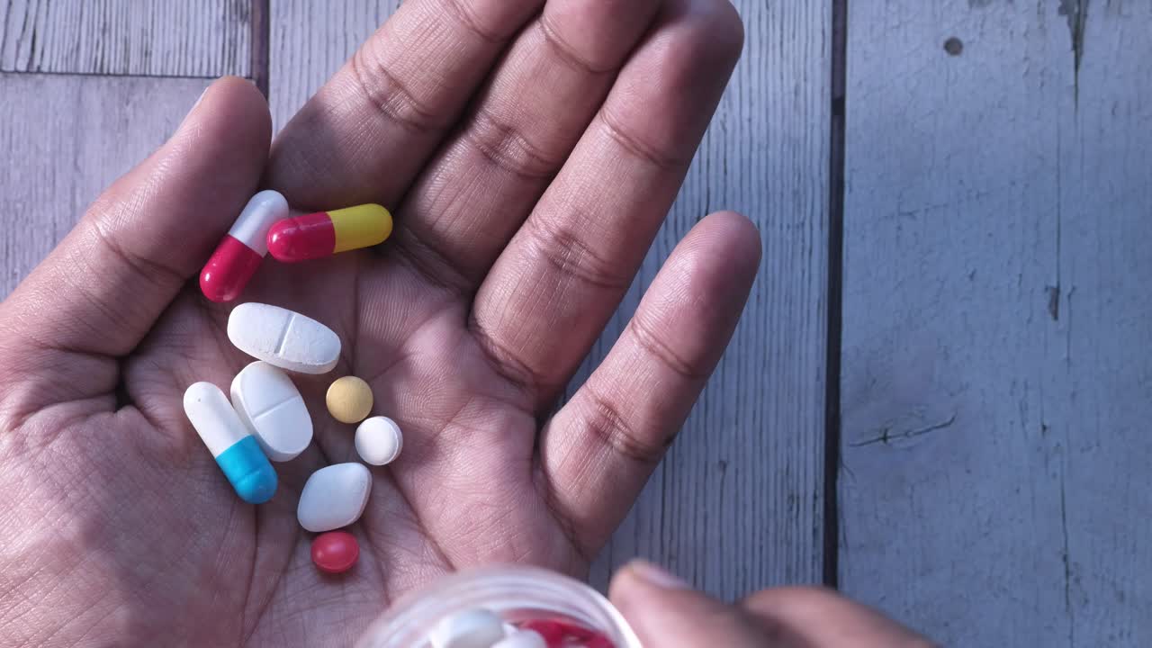 mano con varias pastillas y cápsulas