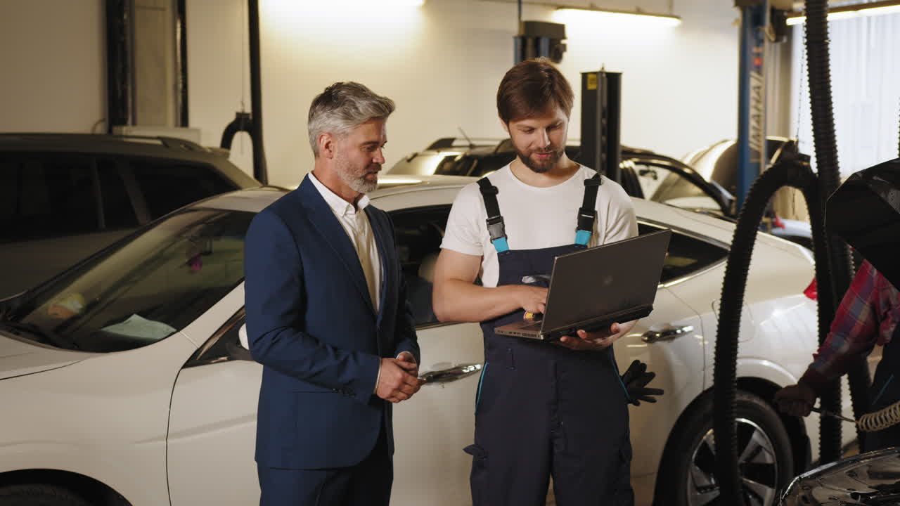 un hombre de negocios discutiendo la reparación de coches con un mecánico.