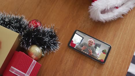 Hombre-Caucásico-Sonriente-Con-Sombrero-De-Papá-Noel-En-Videollamada-Navideña-En-Un-Teléfono-Inteligente