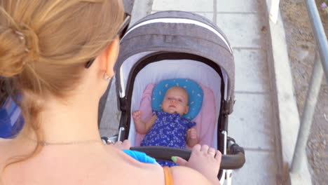 mother pushing baby carriage in the street