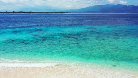 Hermosa-Agua-De-Mar-Turquesa-Cristalina-Inclinada-Hacia-Abajo-Revela-Playa-De-Arena-Blanca