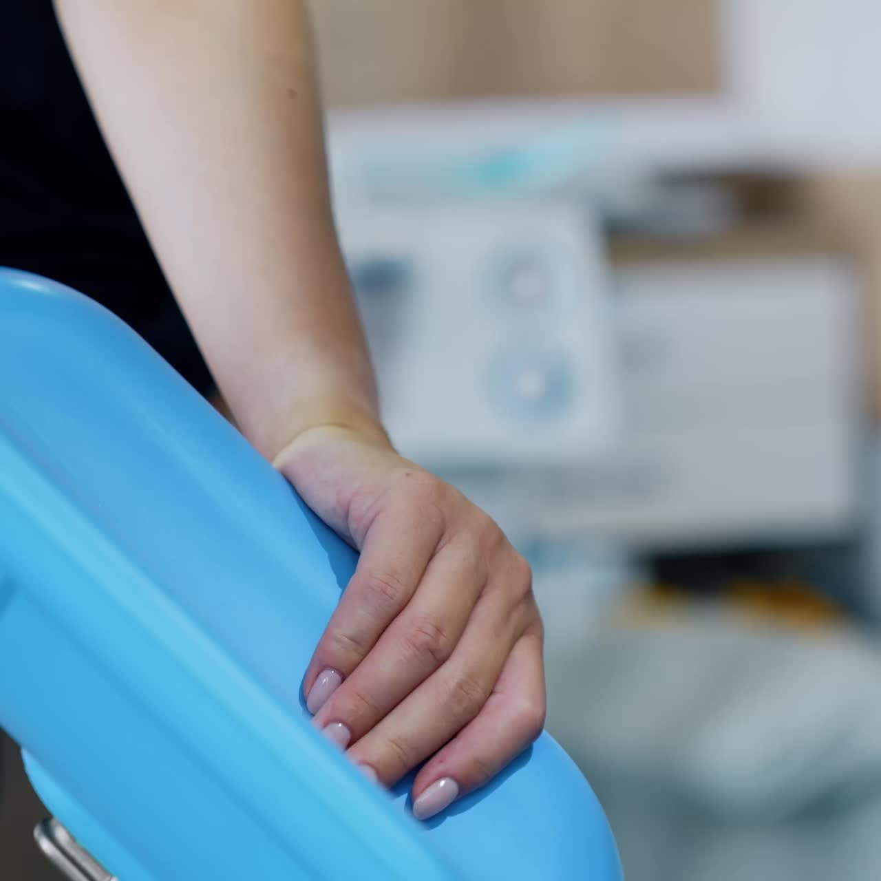 Unrecognized female hand holding by the blue handrail. Lady delivering a baby feeling pain