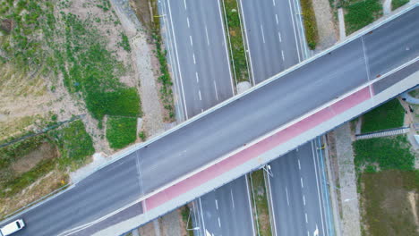 furgoneta blanca conduciendo por un viaducto sobre la autopista, vista aérea de arriba hacia abajo