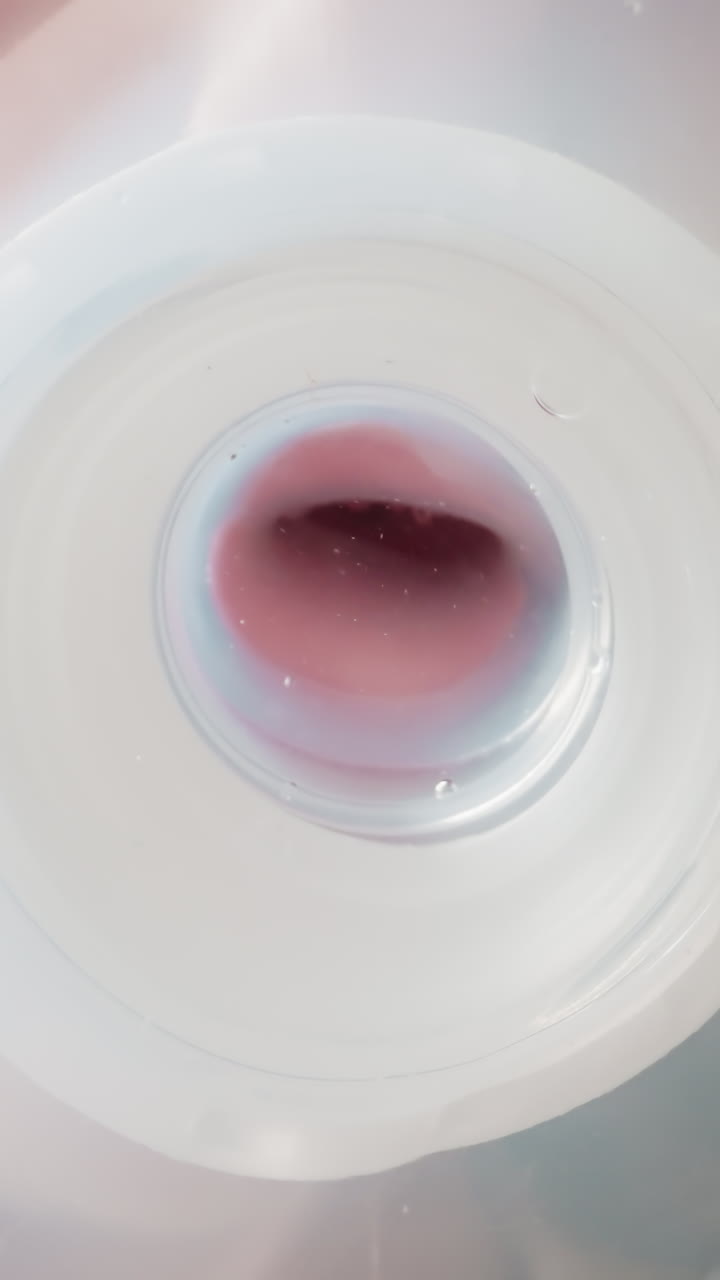 Kid drinks water using white nipple. Little child puts plastic bottle on table and drop runs down. View from inside bottle macro low angle shot