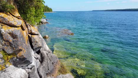 Drone-shot-of-the-coastline-of-Georgian-Bay-with-its-crystal-clear-waters-and-lush-boreal-forest-located-in-Ontario,-Canada