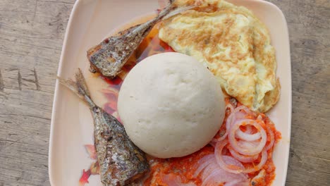 dish with banku, typical ghanaian dumpling, accompanied by fish and other garnishes, african cuisine