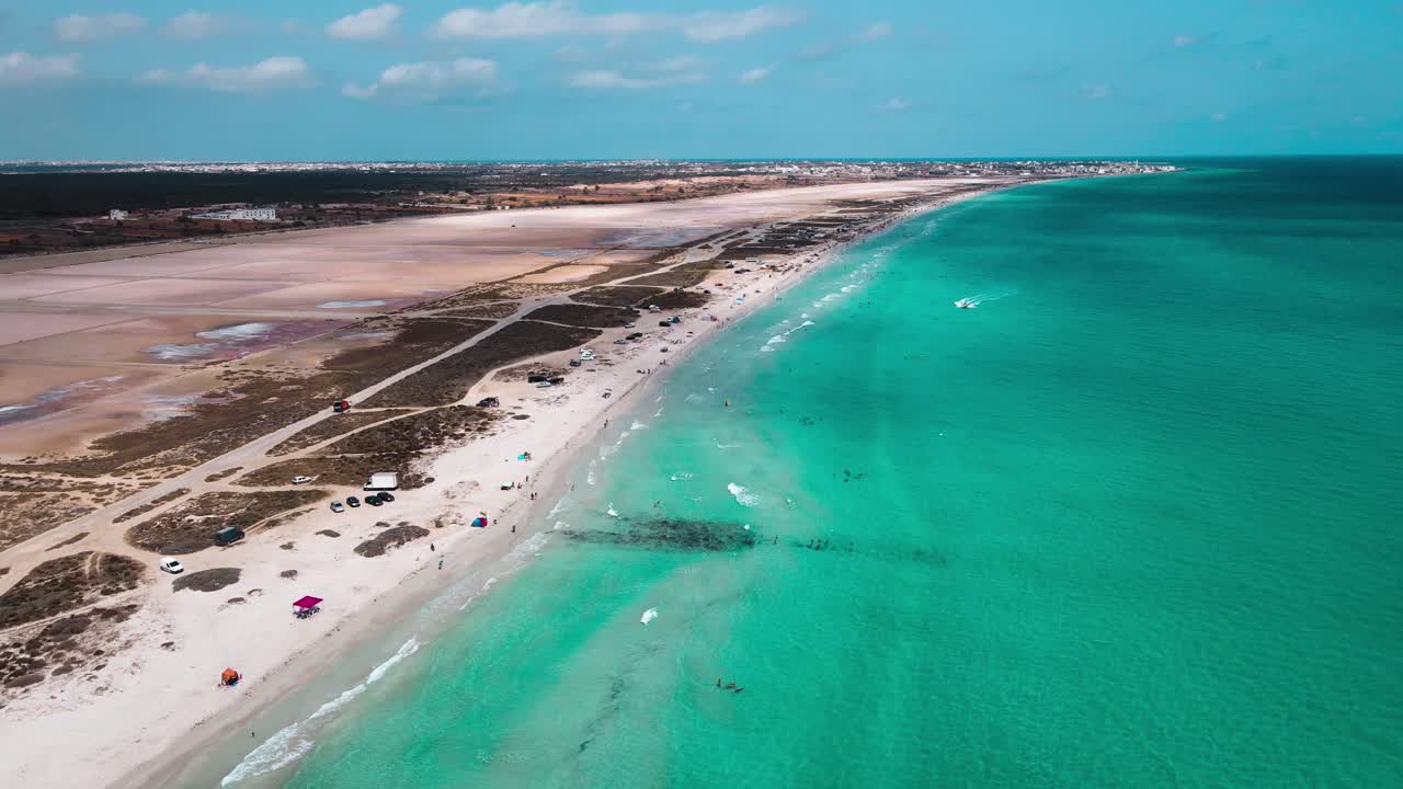 Aerial View of a Turquoise Beach with Swimmers and Boats Along a Vast Coastline