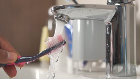 lavar un cepillo de dientes bajo agua corriente
