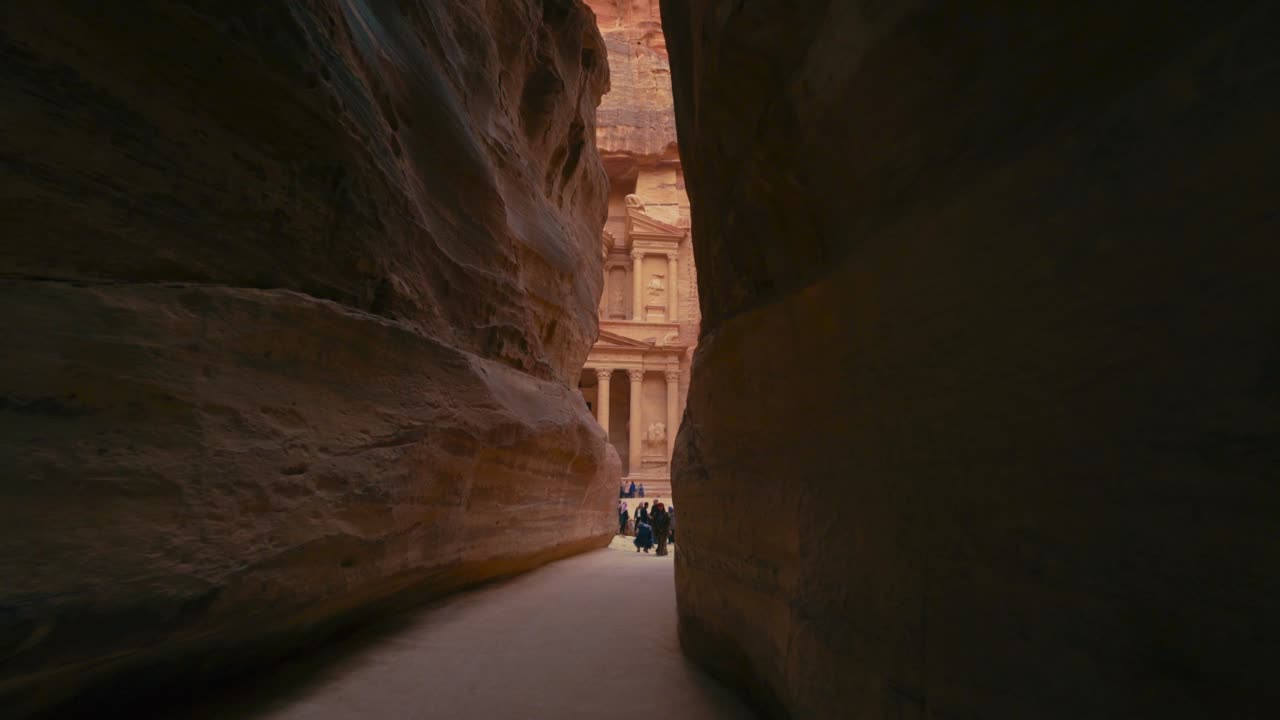 caminando hacia el tesoro a través de la siq en petra, sitio histórico del patrimonio de la unesco tallado en piedra arenisca en jordania. famoso indiana jones última cruzada lugar de filmación y destino turístico khaznet. disparo revelador.