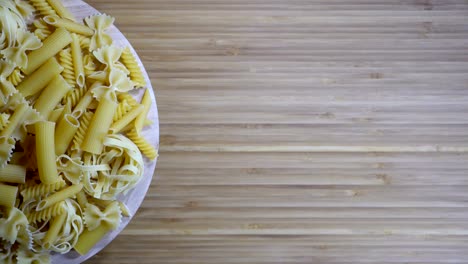 varias pastas crudas girando en una tabla de cortar en blanco, bucle
