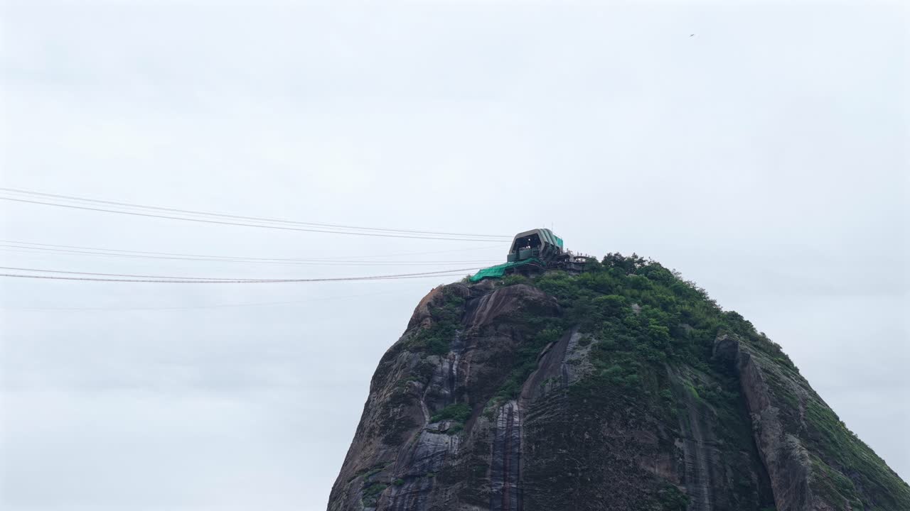 Seilbahnstation des Zuckerhuts auf dem Pão de Açúcar in Rio de Janeiro, Brasilien, mit Granitgipfel und hängenden Seilbahnen, die Teil des Bondinho-Systems sind, statische Drohnen-Teleaufnahme