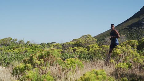 hombre afroamericano de cross country corriendo en el campo en una montaña