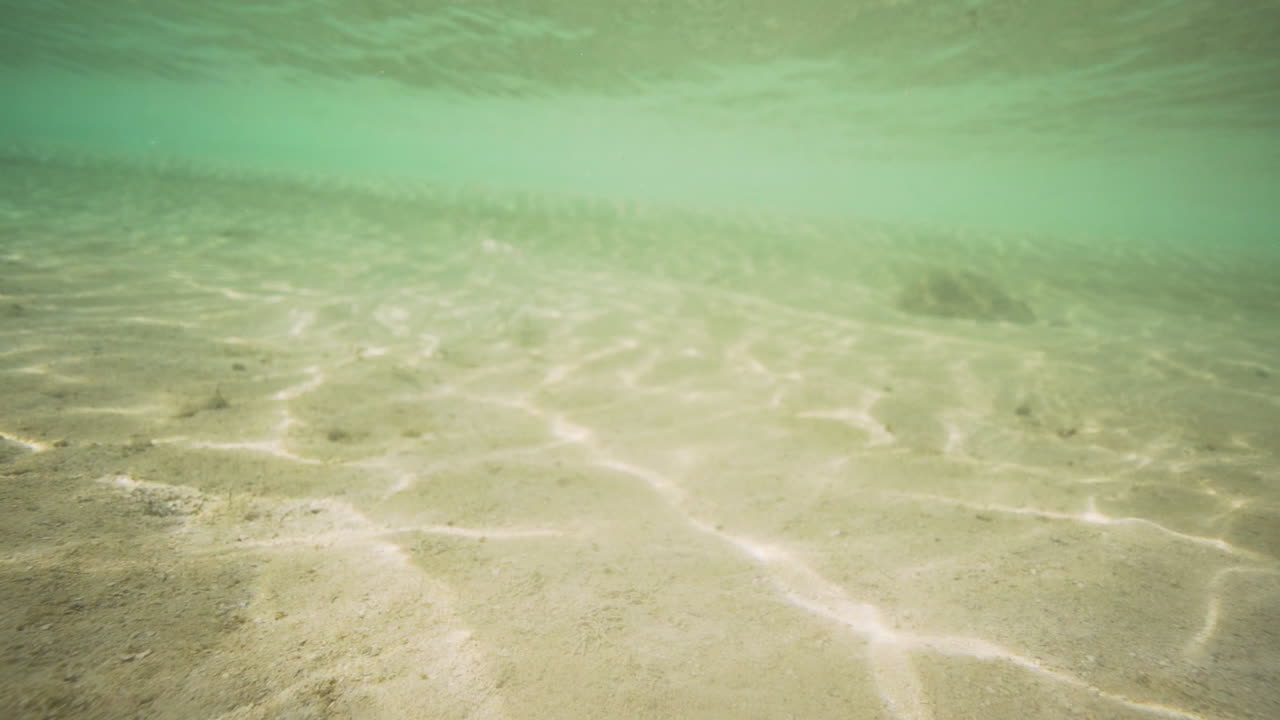 Reflection Of Sunlight On The Sand Under The Blue Sea. - underwater shot