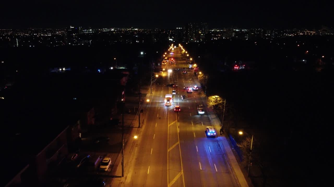 accidente de coche en una carretera, con vehículos policiales y una ambulancia con luces de sirena encendidas, por la noche