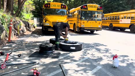 mechanic provides maintainance school bus tires in parking lot. slow motion