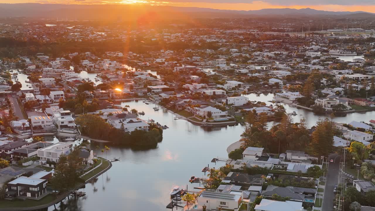 Aerial view of Gold Coast canals at sunset, highlighting serene waterways and vibrant urban landscape with warm, golden lighting