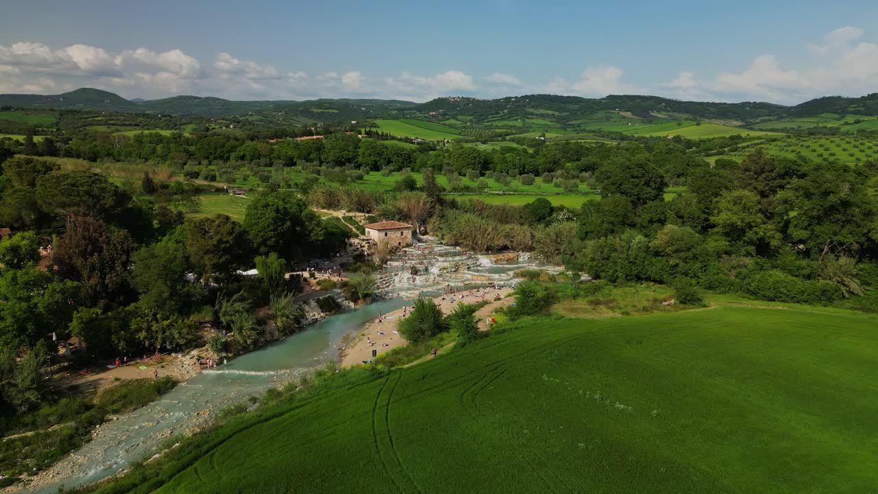 Vista drone delle terme di Saturnia con piscine termali naturali, acqua turchese che scorre e paesaggio della campagna toscana in Italia