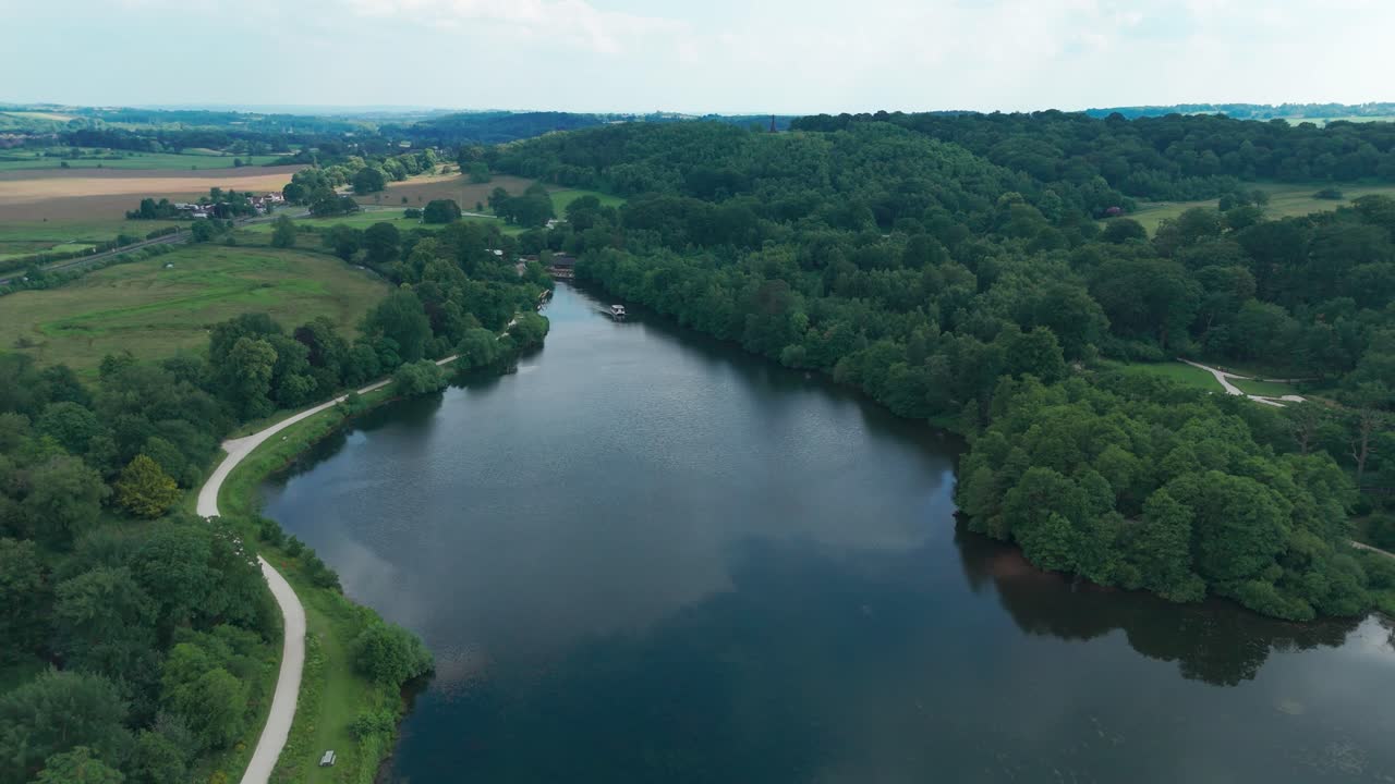 vista panorámica del lago trentham con arbustos verdes en inglaterra