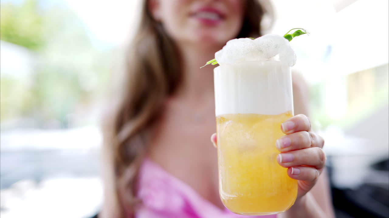 Woman holding a summer white and orange cocktail with whiskey and peach juice, slow motion