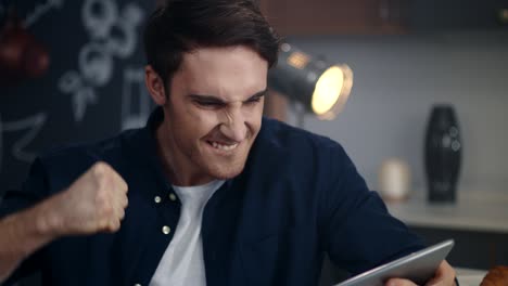 portrait of excited man getting good news on tablet computer in home office.