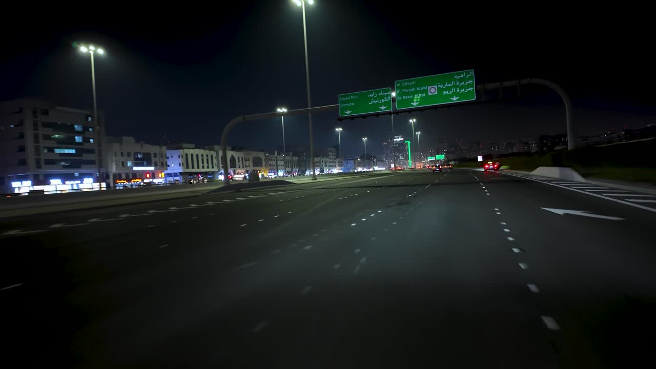 Driving along a highway towards the Abu Dhabi city center at nighttime in the United Arab Emirates