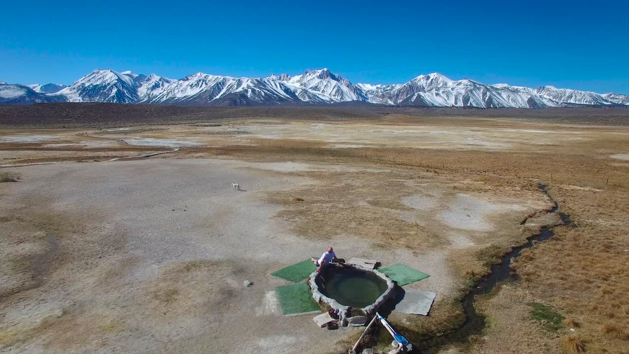 una antena sobre un hombre en una piscina caliente natural en las montañas de sierra nevada cerca de mammoth california