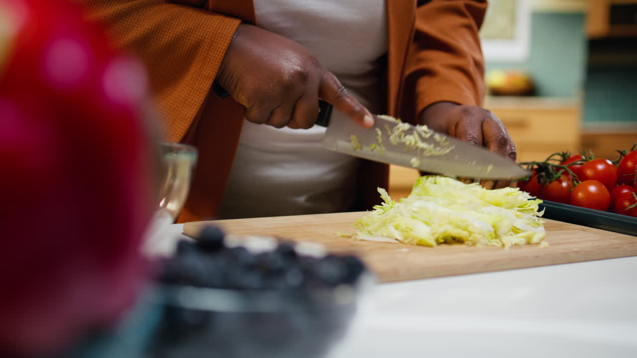 Food blogger di colore che taglia lattuga iceberg sul tagliere
