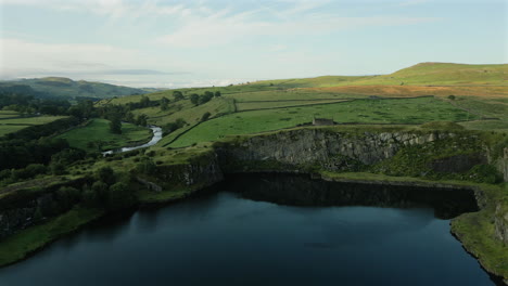 rising establishing drone shot over disused quarry at golden hour in yorkshire dales