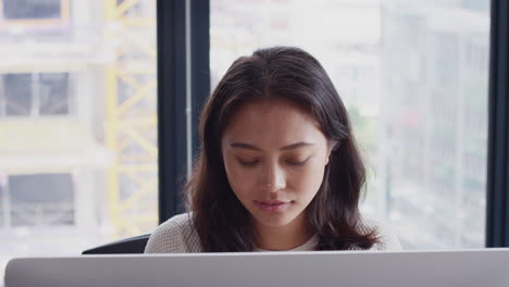 Junge-Kreative-Asiatische-Frau,-Die-In-Einem-Büro-Auf-Den-Computerbildschirm-Schaut-Und-Kaffee-Trinkt,-Aus-Nächster-Nähe