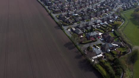 Urbanización-Rural-Vista-Aérea-Volando-Por-Encima-De-Inglaterra-Tierras-De-Cultivo-Aradas-Viviendas-Comunitarias-Residenciales